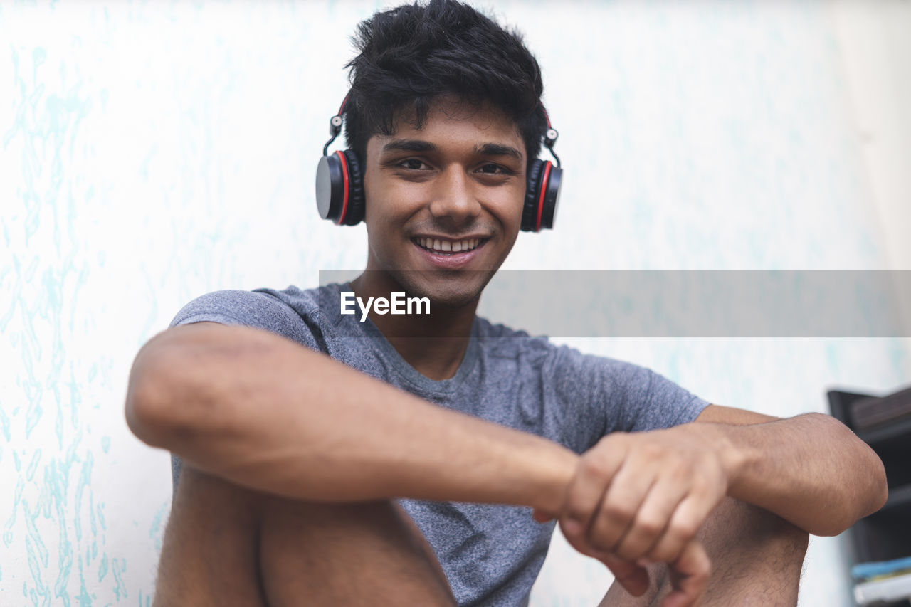 Glad indian man dances, makes movements to music, has modern stereo headphones, smiles positively