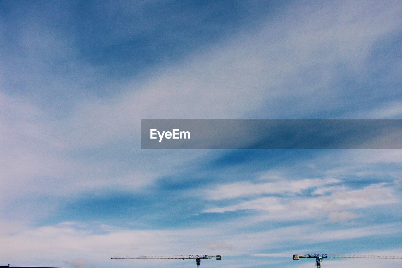 Low angle view of crane against cloudy sky