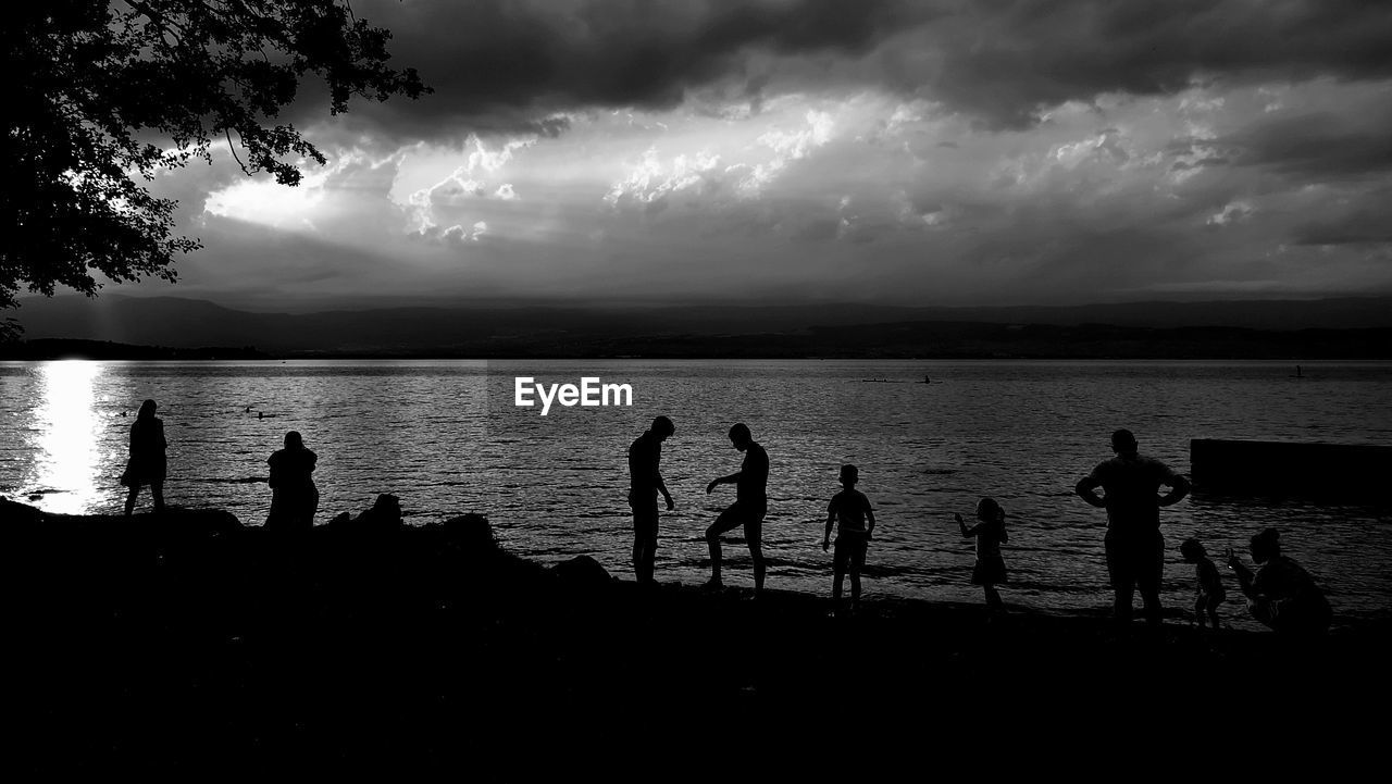 Silhouette people on beach against sky