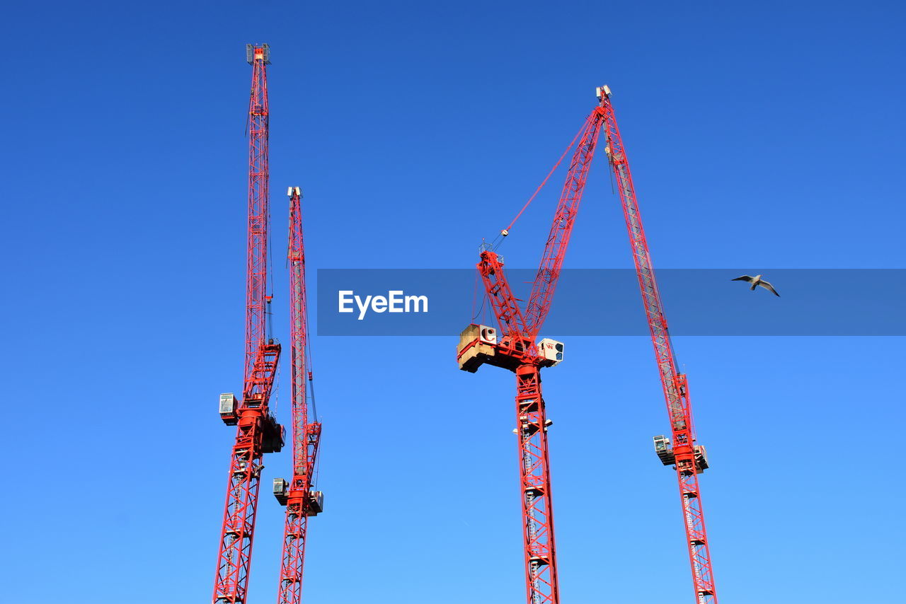 crane - construction machinery, machinery, sky, blue, industry, construction industry, clear sky, construction site, architecture, nature, development, mast, sunny, business, no people, metal, built structure, overhead power line, outdoors, vehicle, construction equipment, day, construction machinery, copy space, low angle view, electricity, line, business finance and industry, equipment, tower, freight transportation