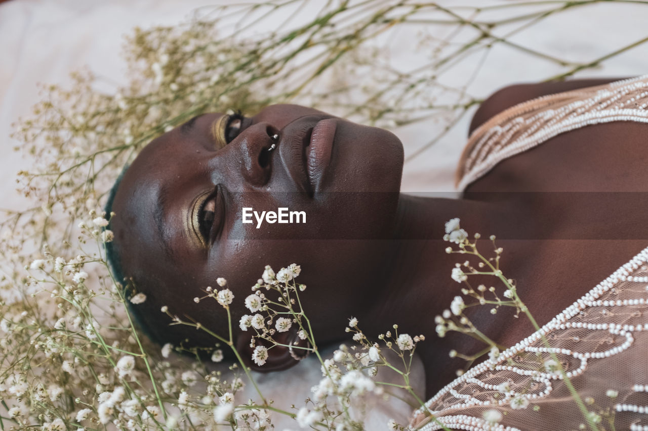 CLOSE-UP PORTRAIT OF WOMAN LYING DOWN ON PLANT