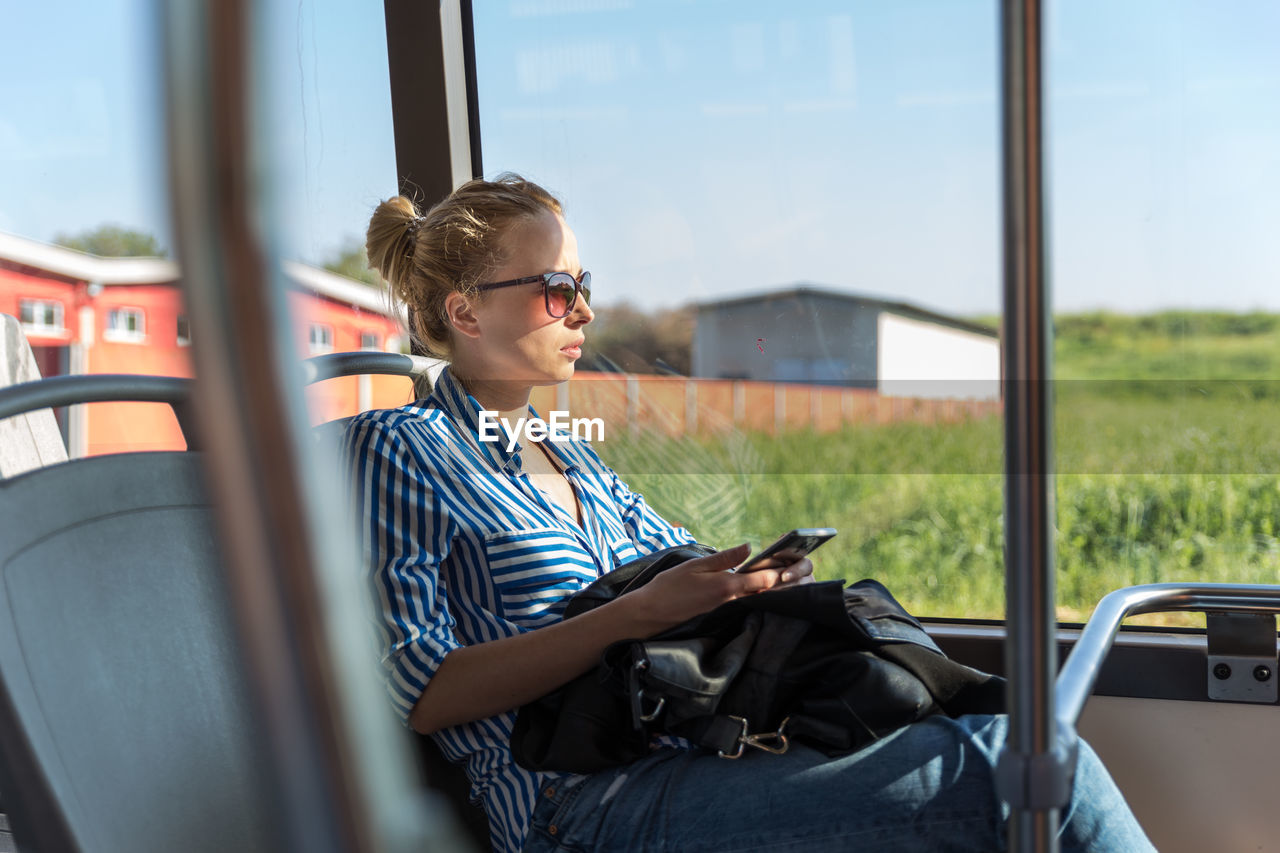 Beautiful woman using smart phone while sitting in bus