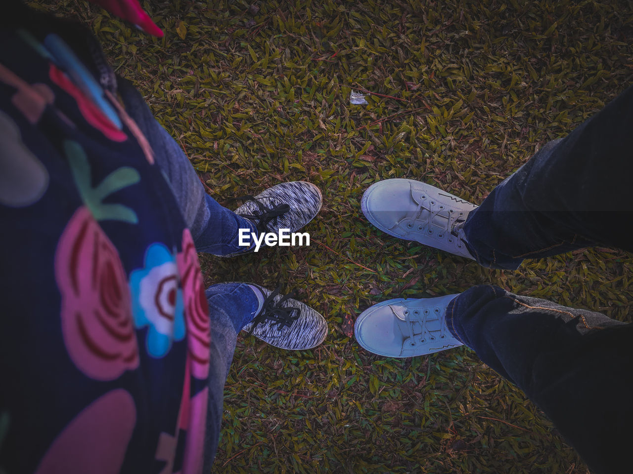 Low section of people wearing shoes while standing on grass