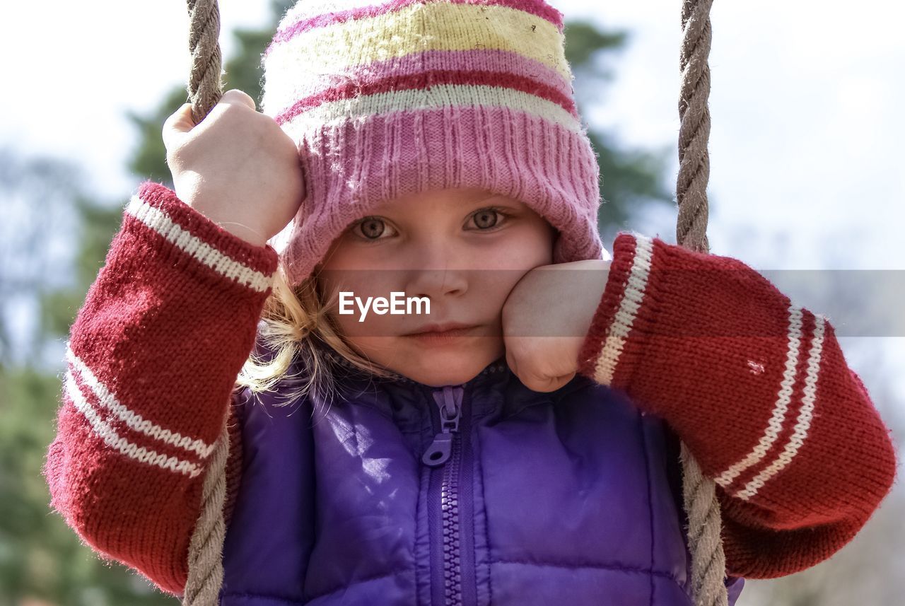 Portrait of cute girl sitting on swing outdoors