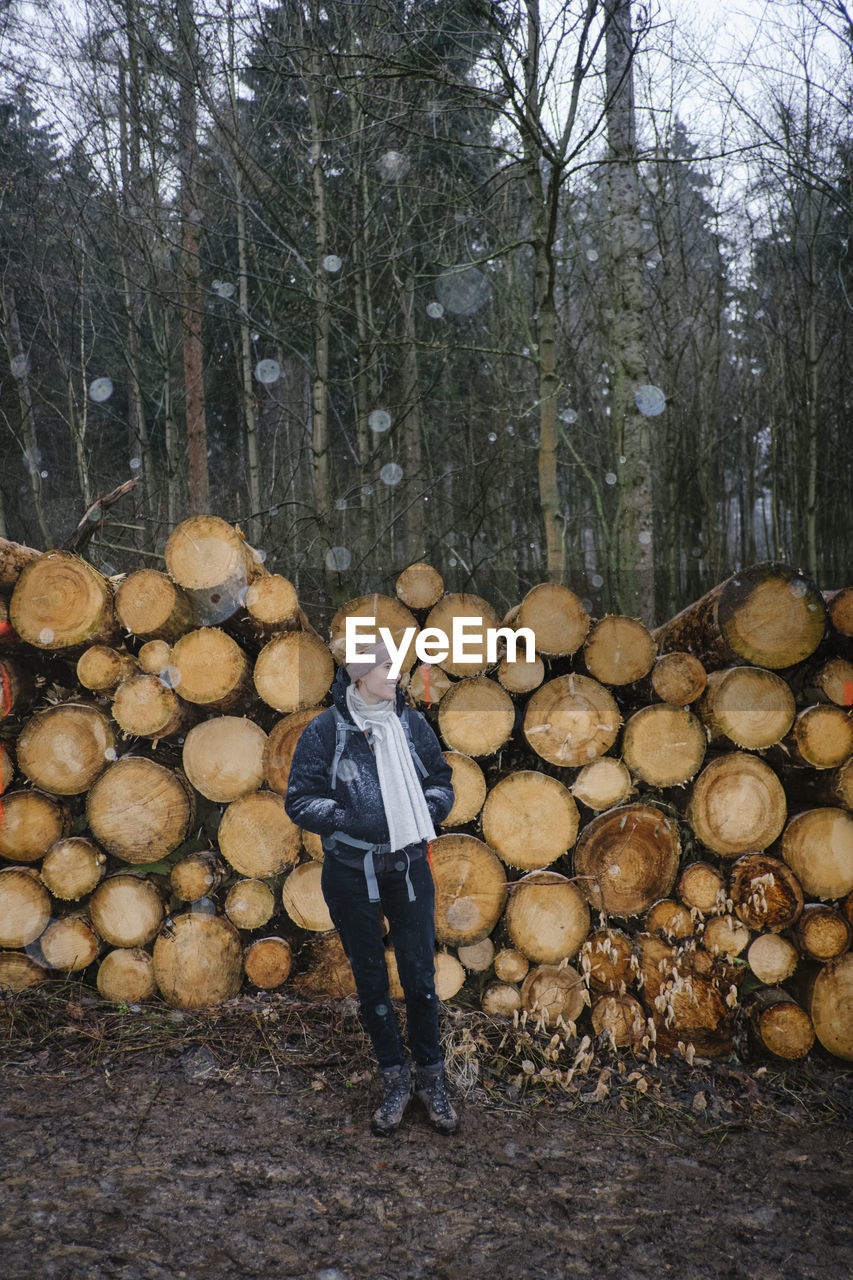 Full length of man standing on log in forest