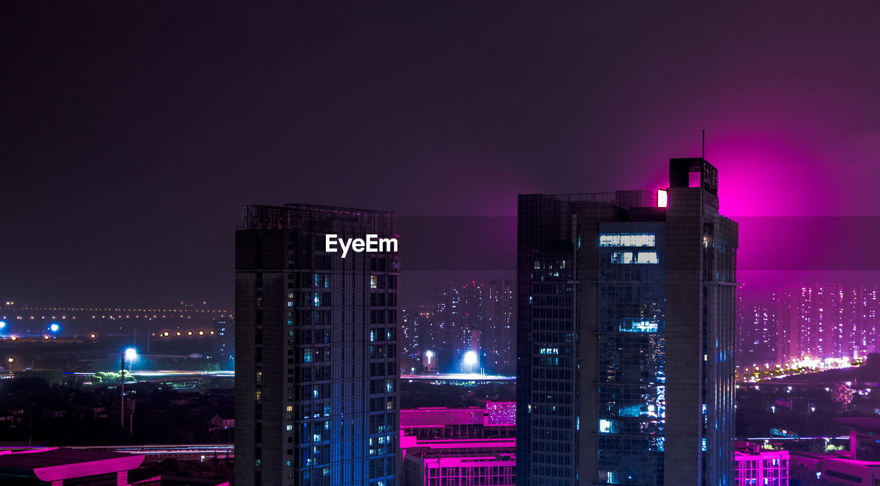 Illuminated buildings against sky at night