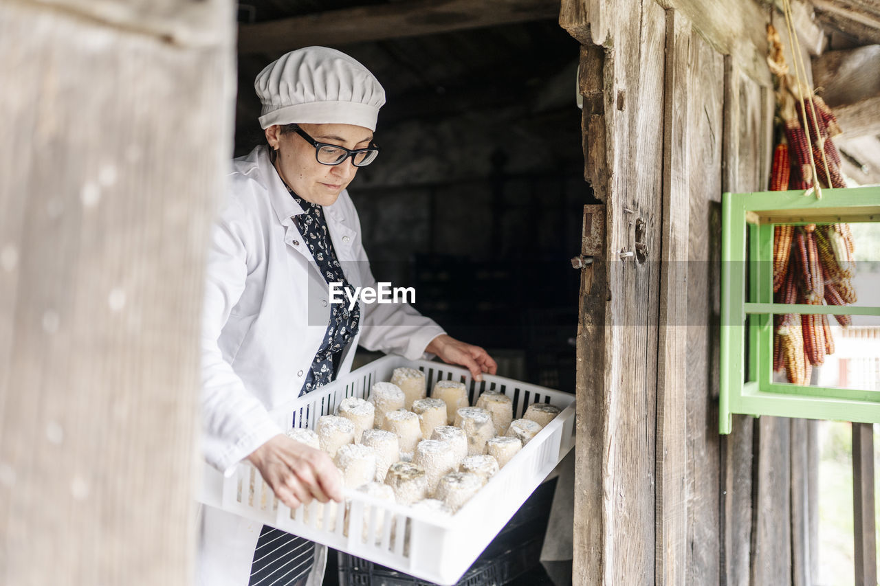 Female owner holding cheese tray at doorway