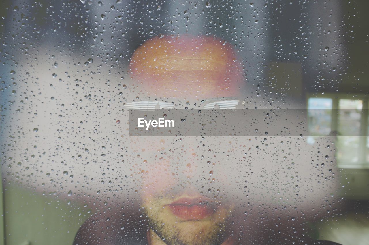 Close-up of waterdrops on glass a man