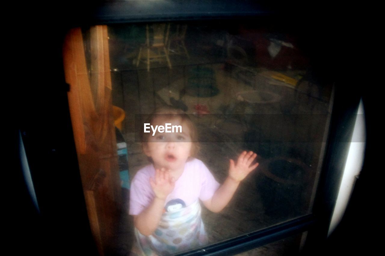 Portrait of girl crying seen through window