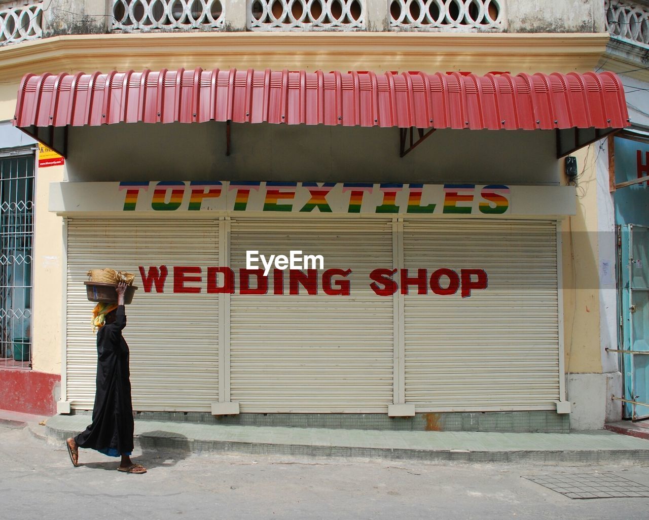 Side view of woman holding basket while walking by closed wedding shop