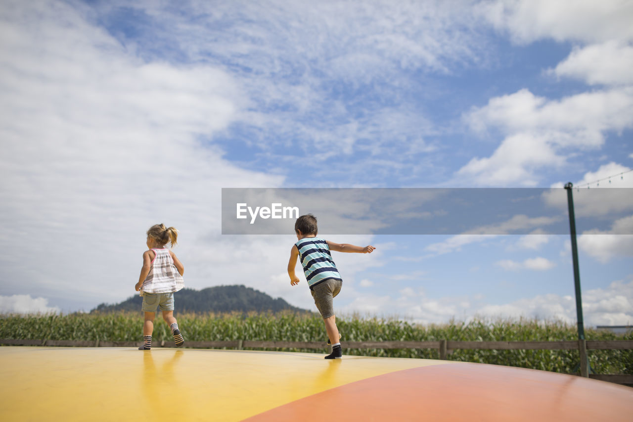 Boy and girl running on trampoline, outdoors in rural area. on the move