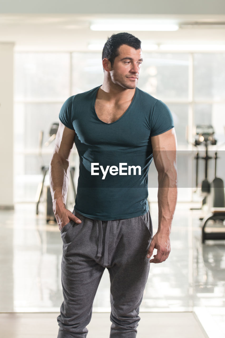 Muscular man looking away while standing in gym