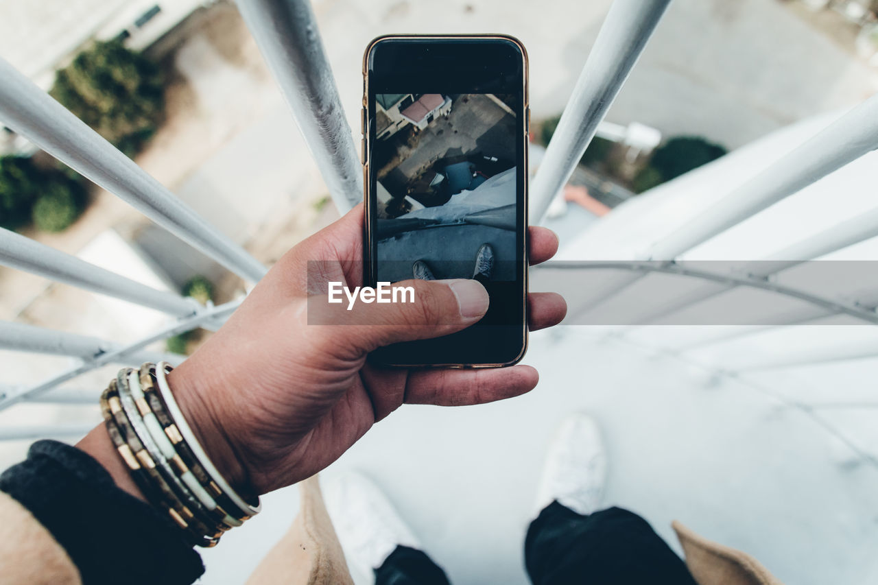 Low section of man photographing from mobile phone at balcony