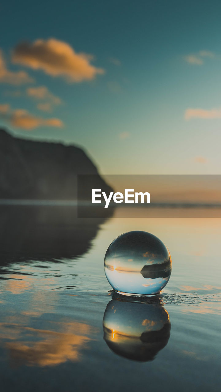 Lensball on beach against sky during sunset