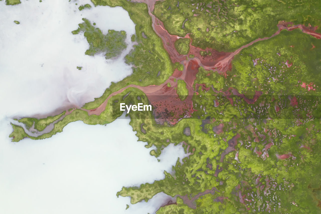 Drone view of rough rocky brown formations surrounded by lush green plants covered with thick fog in nature of iceland