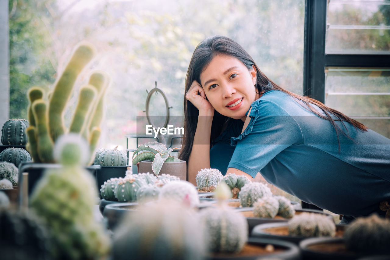 PORTRAIT OF SMILING YOUNG WOMAN SITTING OUTDOORS