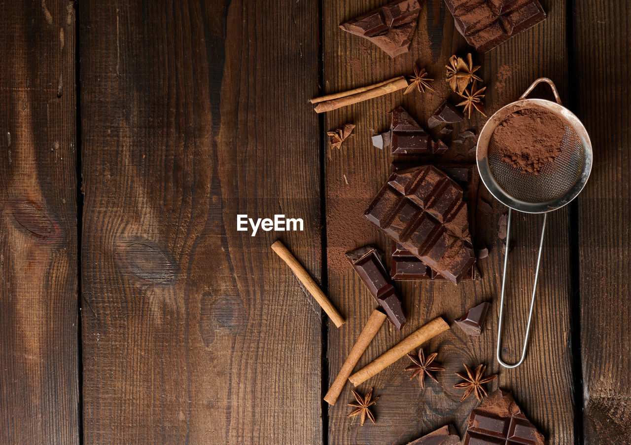 Broken pieces of dark chocolate, cinnamon sticks and star anise on a brown wooden 