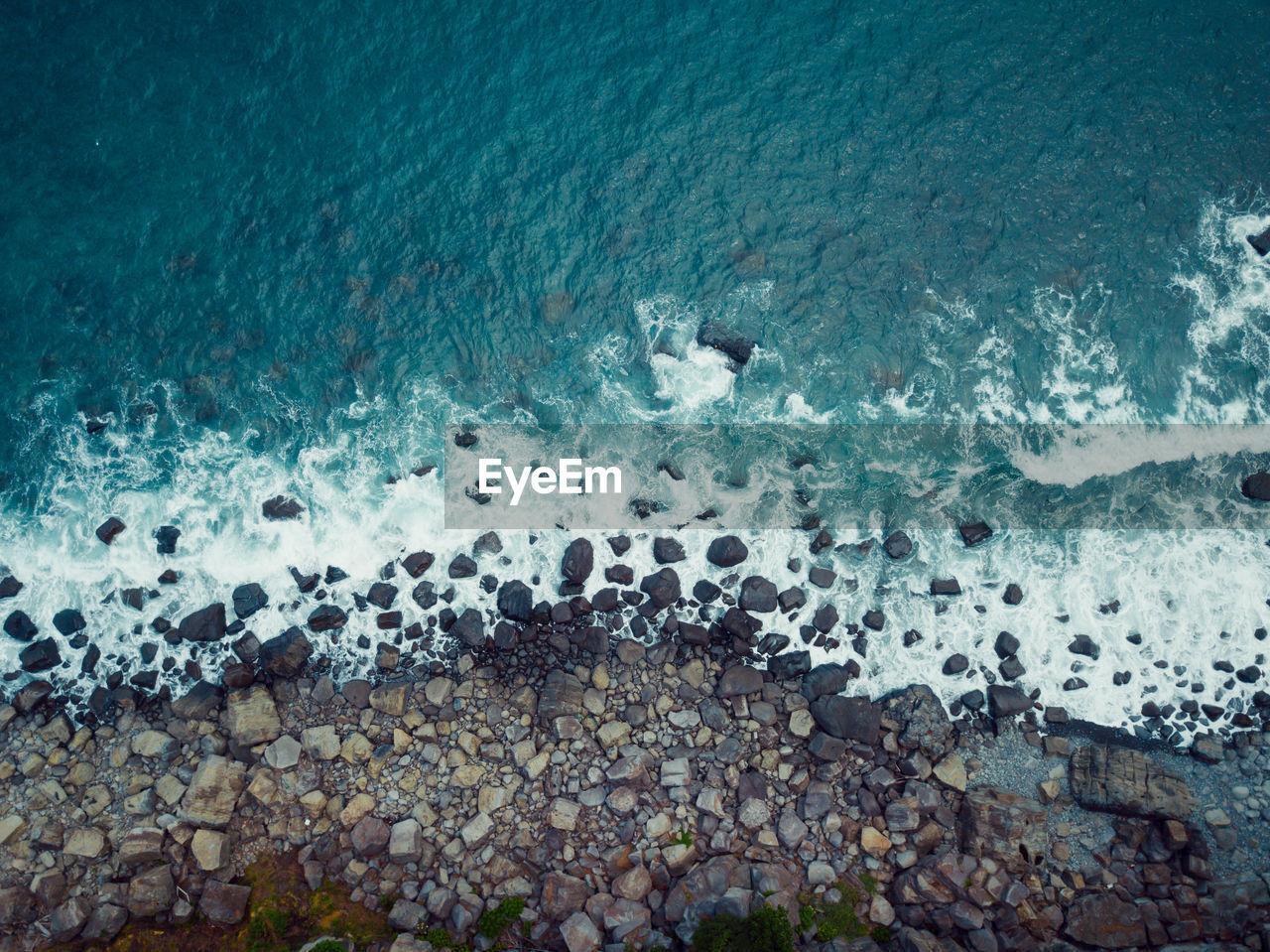 HIGH ANGLE VIEW OF PEBBLES ON SHORE AT SEA