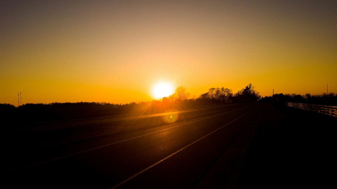 Empty road against sky during sunset