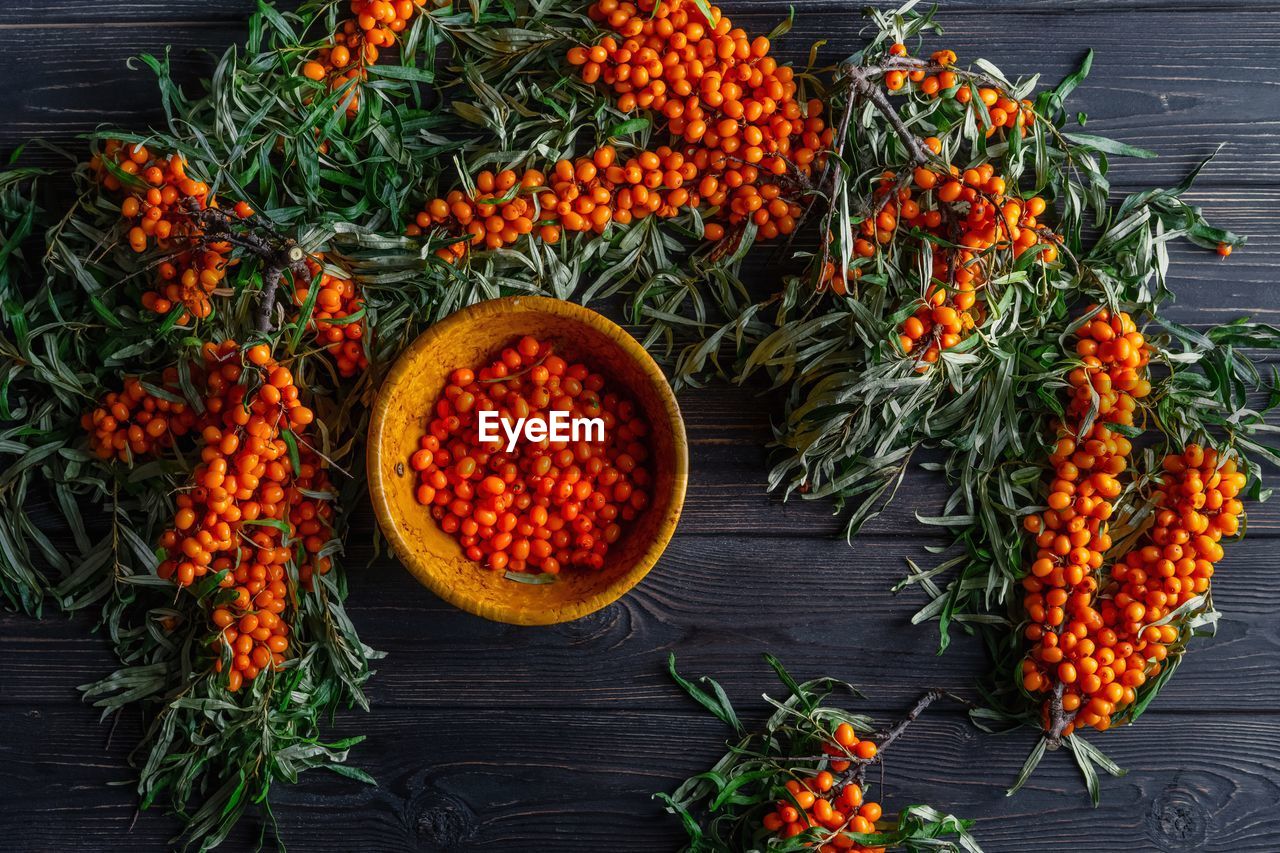 Sea buckthorn berries with branches on dark wooden rustic background 