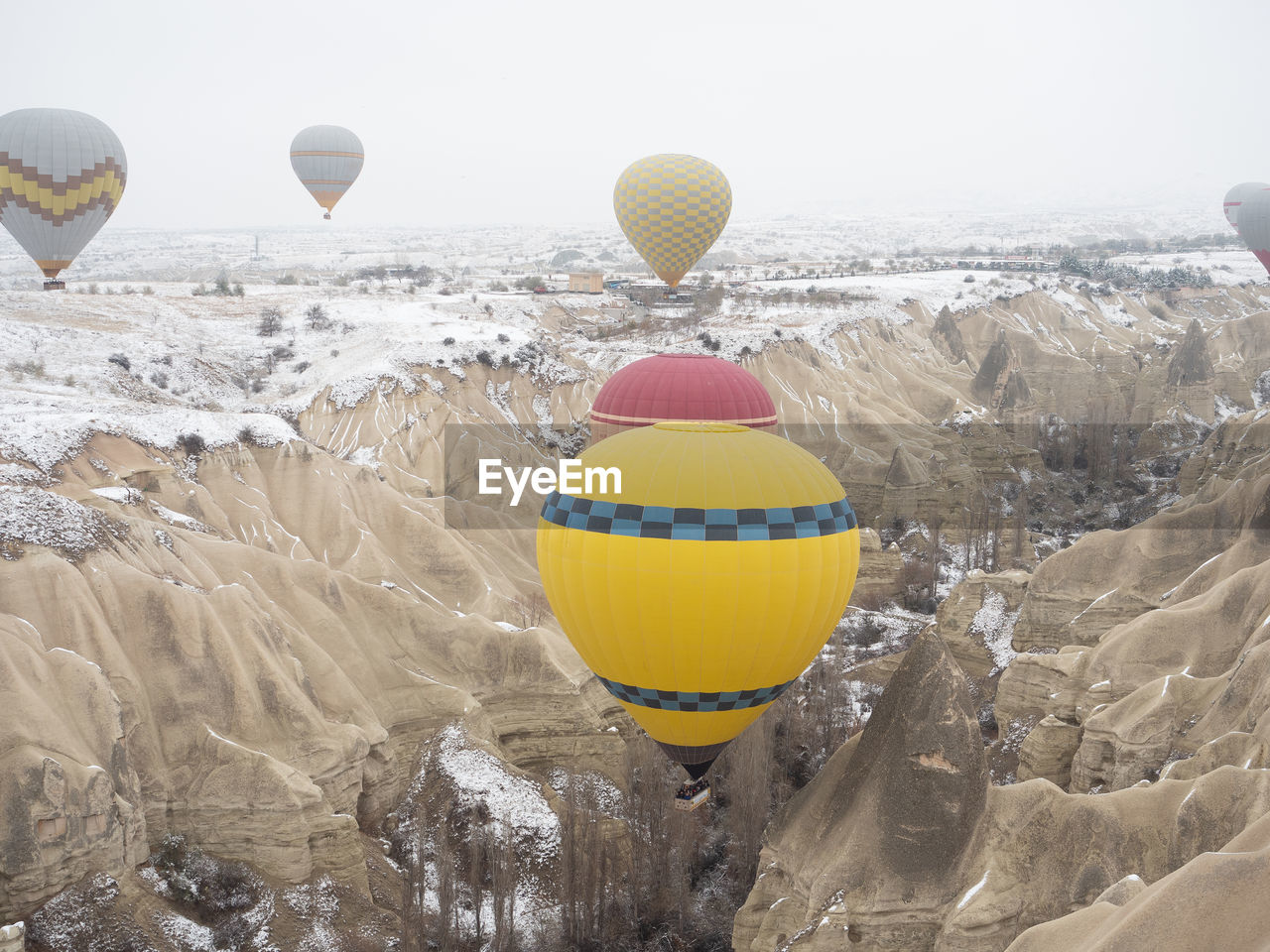 Bright color hot air balloons venturing into turkey cappadocia snowy valley in foggy winter morning