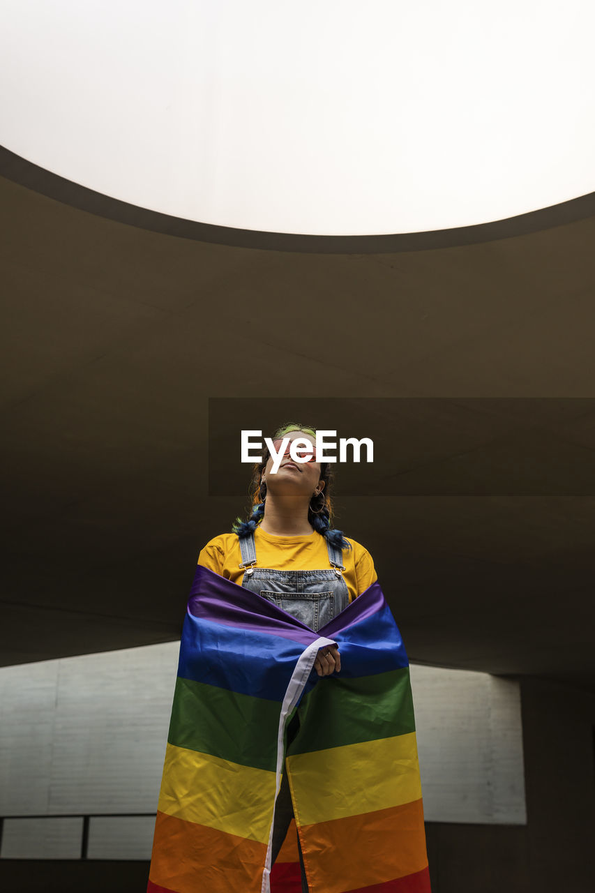 Young woman standing with rainbow flag