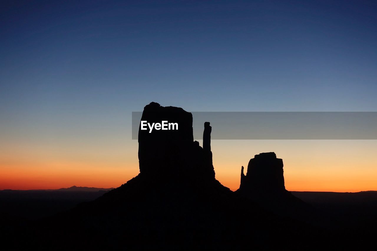 Silhouette rocks against clear sky during sunset