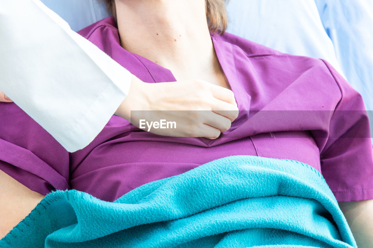 LOW SECTION OF WOMAN RESTING ON PINK BED