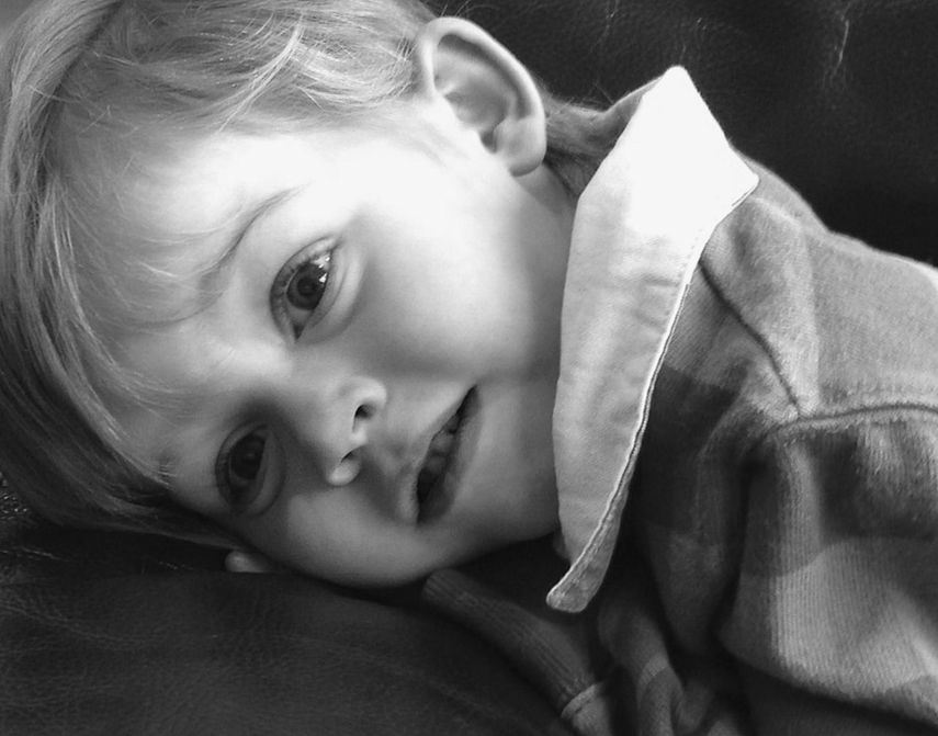 Close-up of boy leaning on bed while looking away