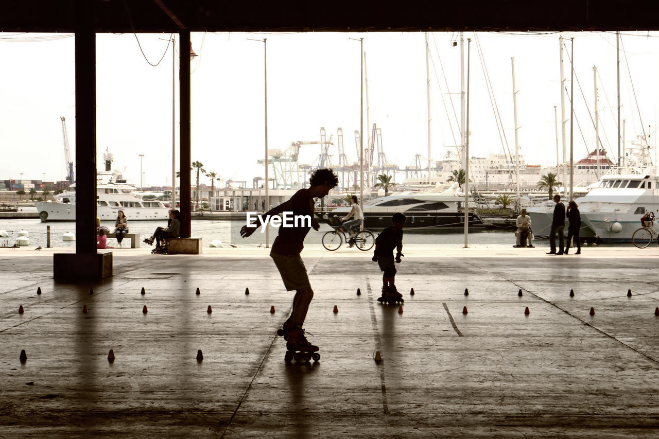 Silhouette woman and boy roller skating on walkway