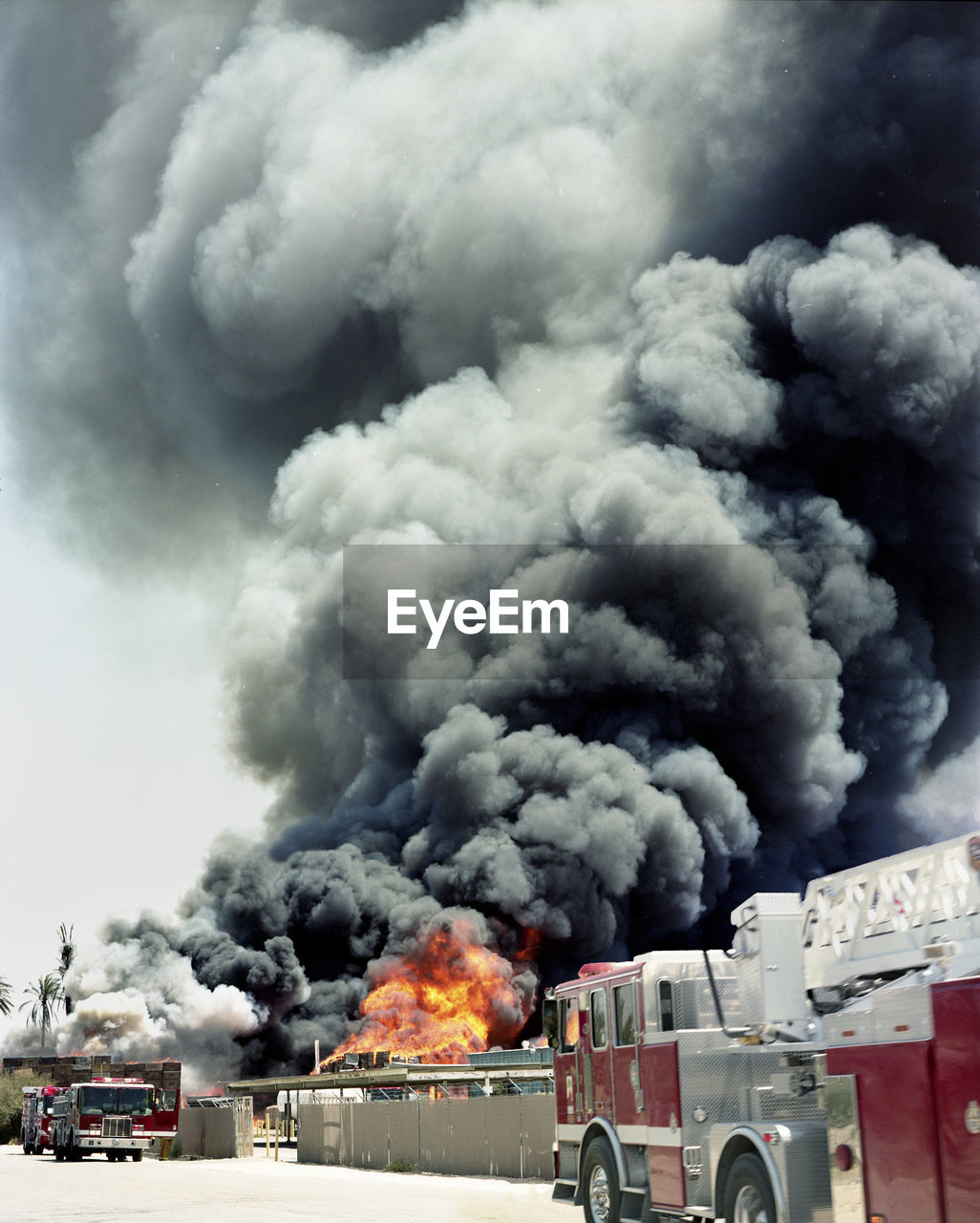 Fire engines against smoke emitting from burning crates in factory