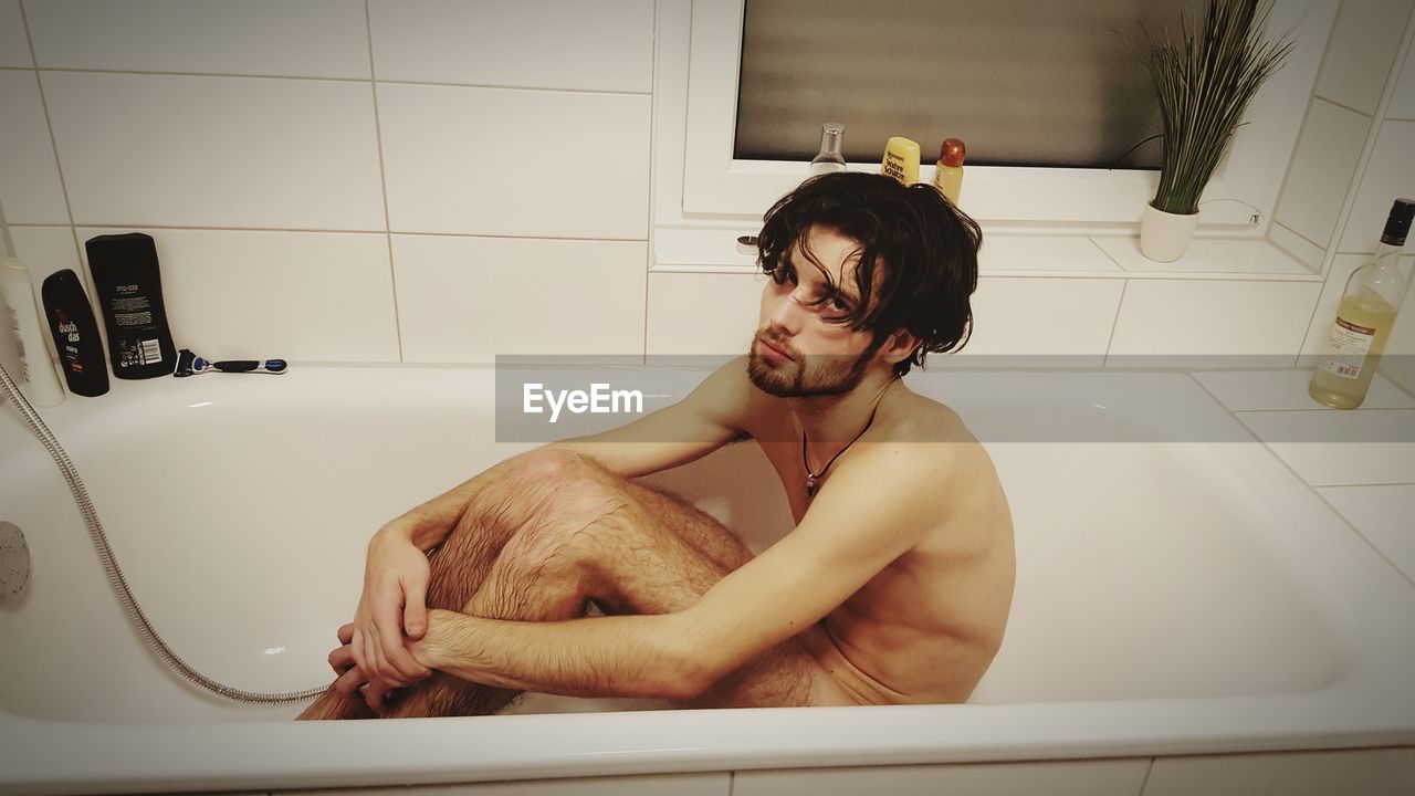 Portrait of naked man sitting in bathtub