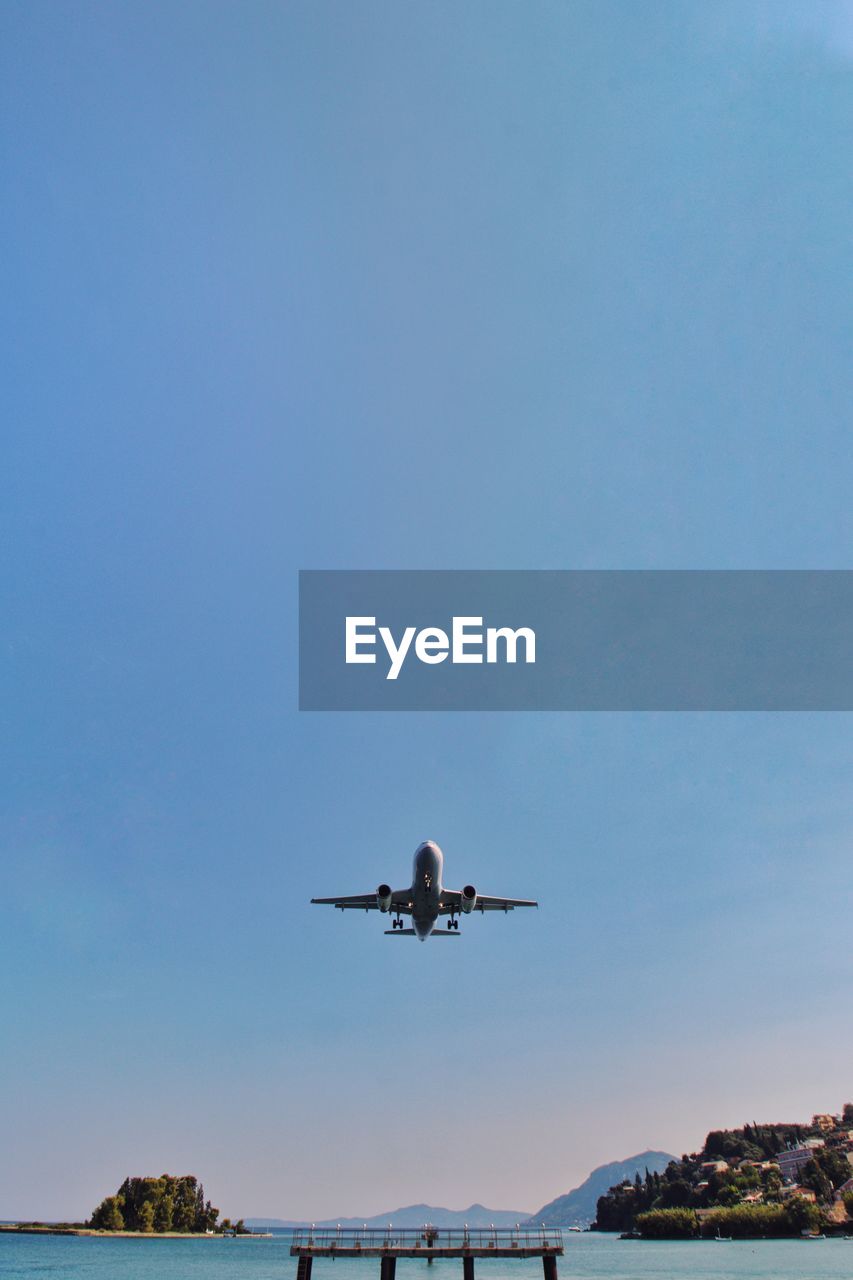 Low angle view of airplane flying in clear blue sky