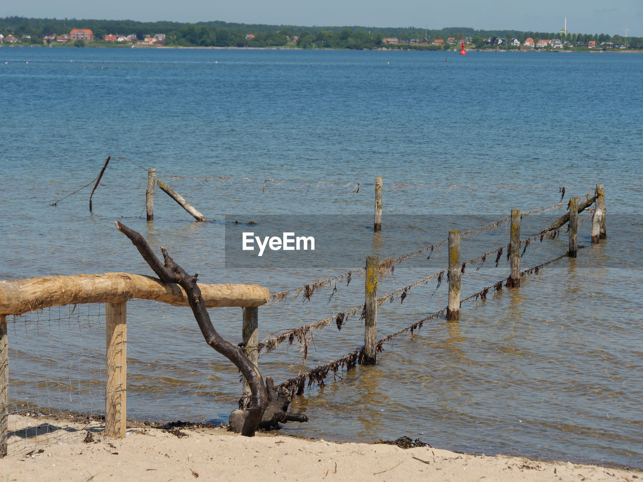 WOODEN POSTS ON BEACH WITH LAKE