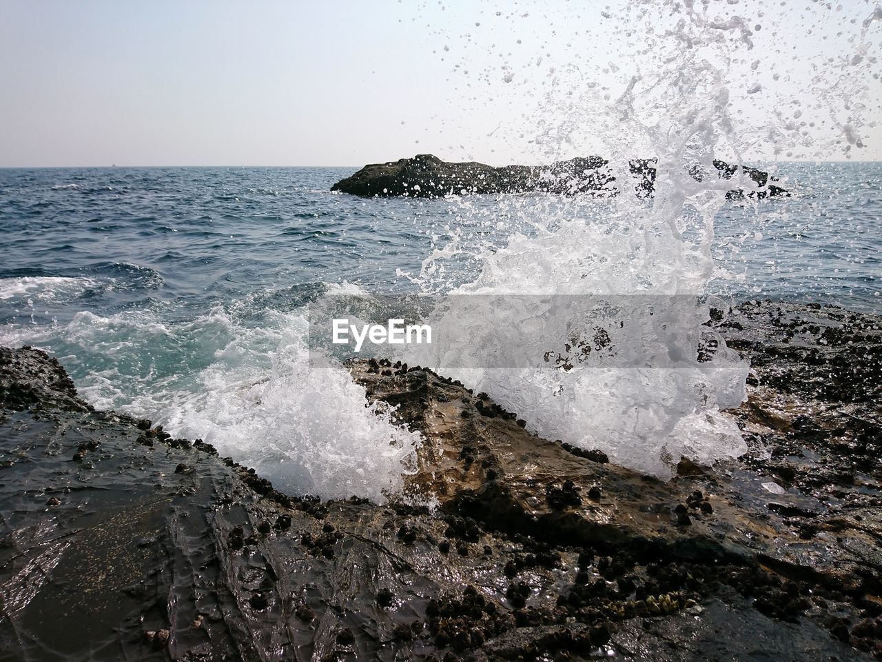 WAVES SPLASHING ON ROCKS AGAINST SKY