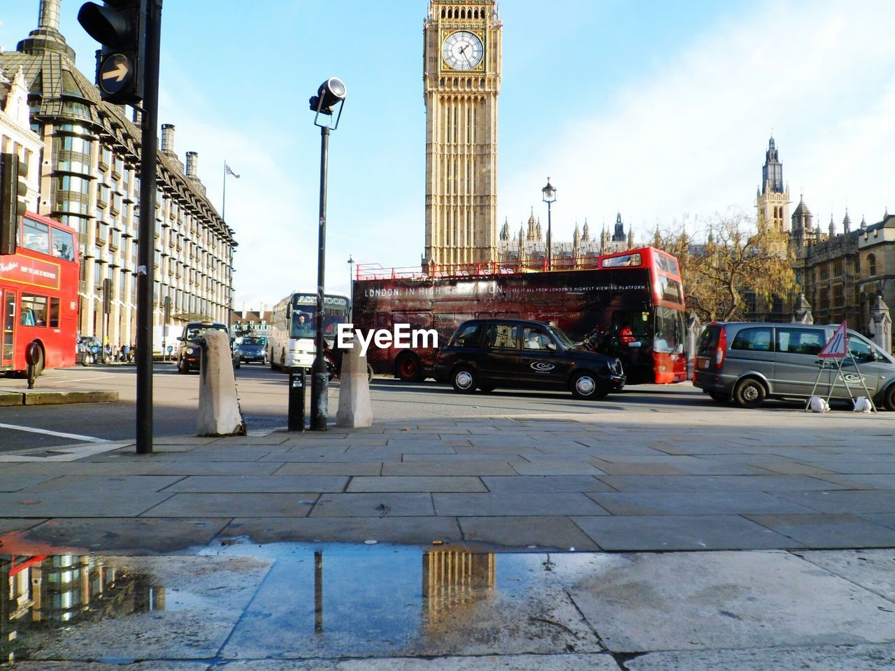 Vehicles on road against big ben in city against sky