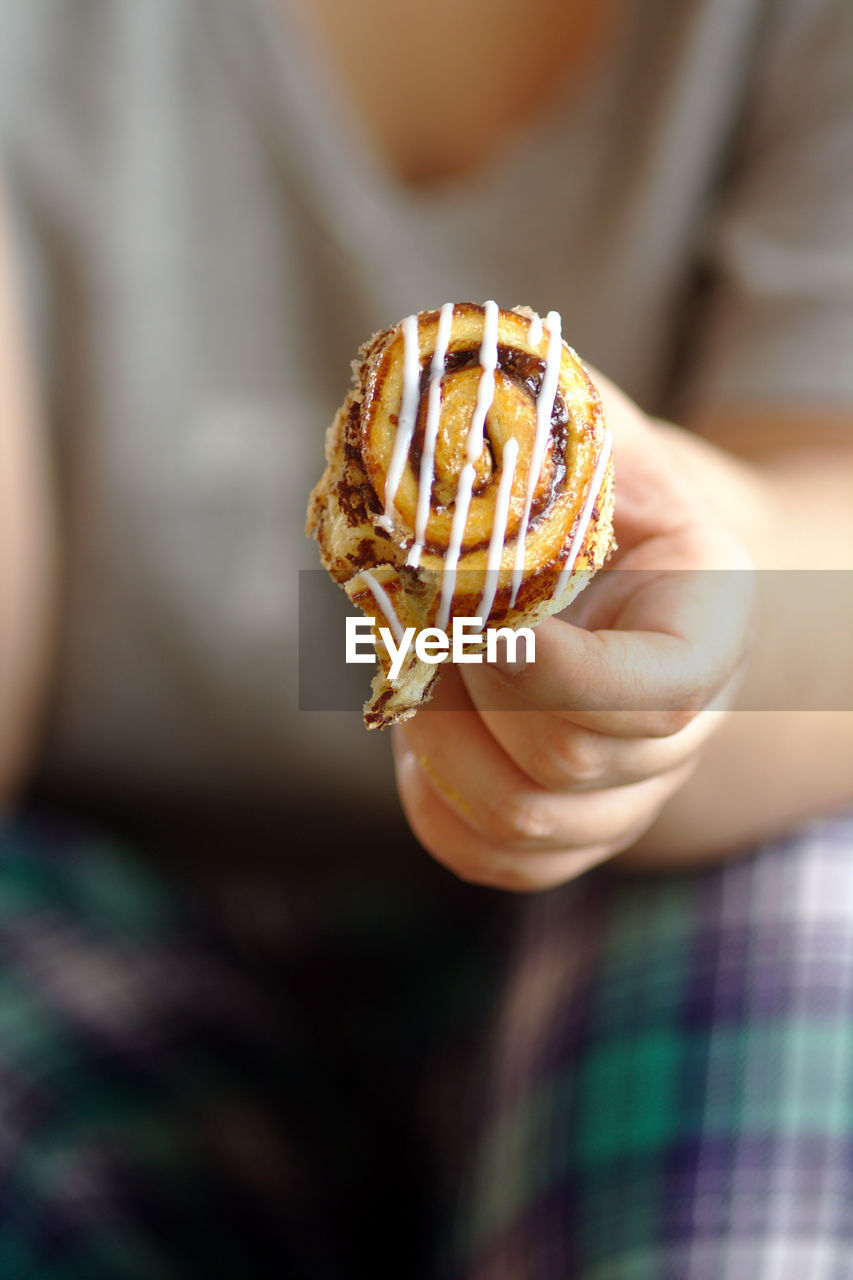 Close-up of hand holding cinnamon roll