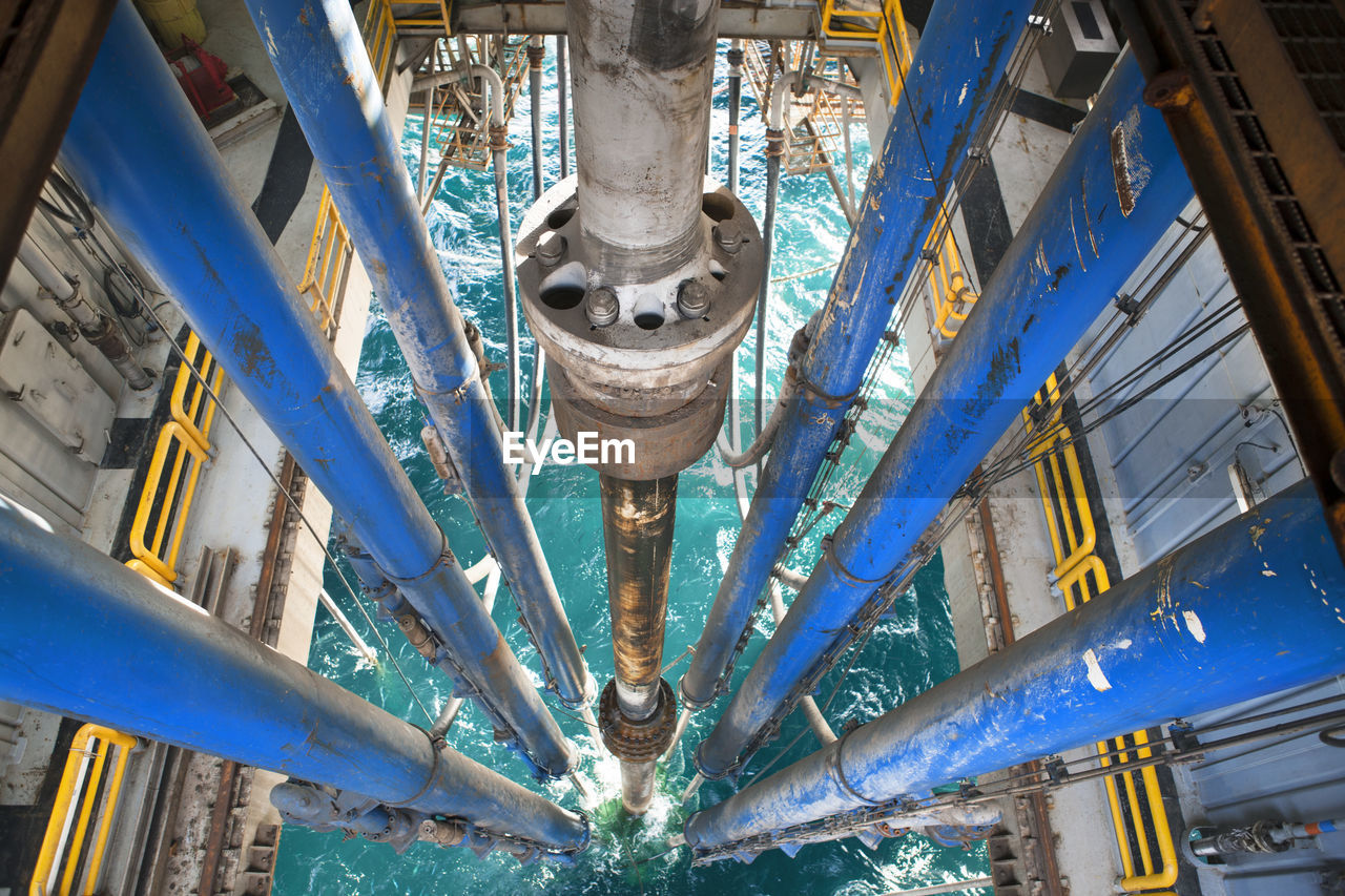 High angle view of drilling riser and pipes in sea at oil rig