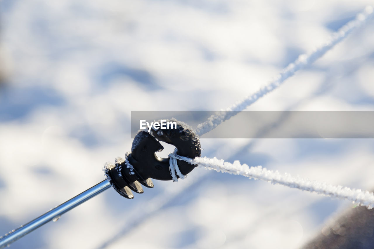 CLOSE-UP OF ROPE TIED TO METAL POLE AGAINST SKY