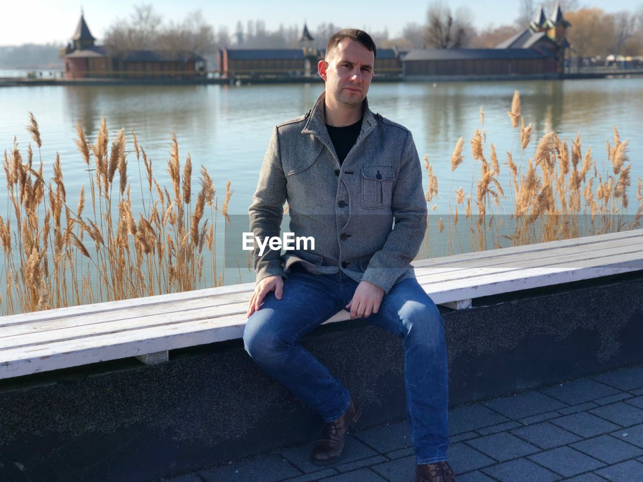 Portrait of man sitting by lake in city