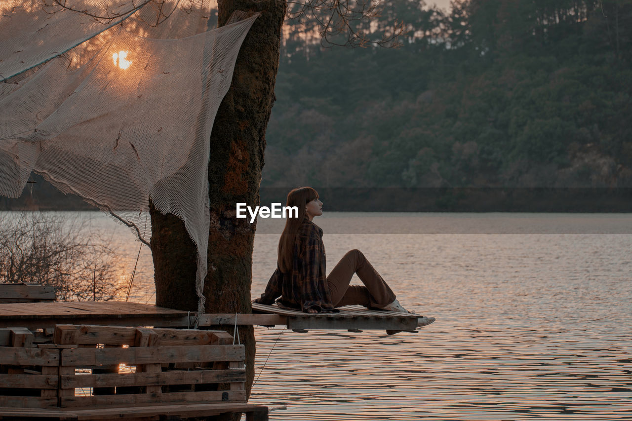 Rear view of woman standing by lake