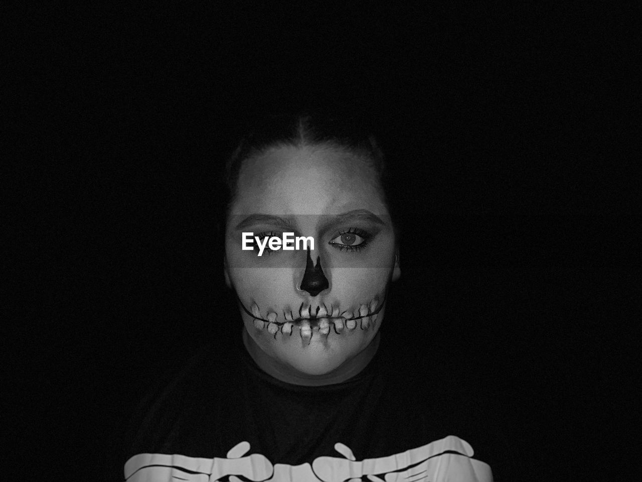 Portrait of young woman with spooky make-up against black background
