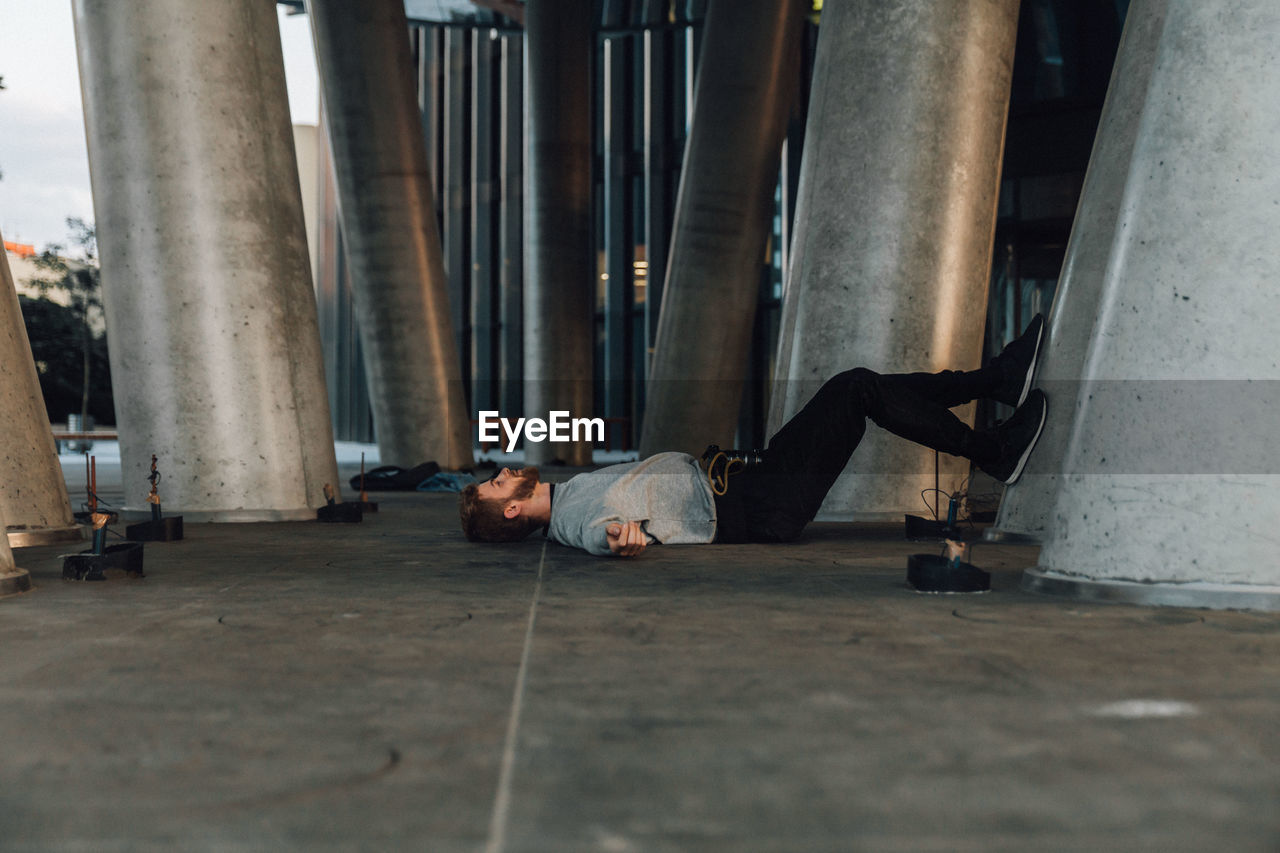 Man sleeping on street by columns