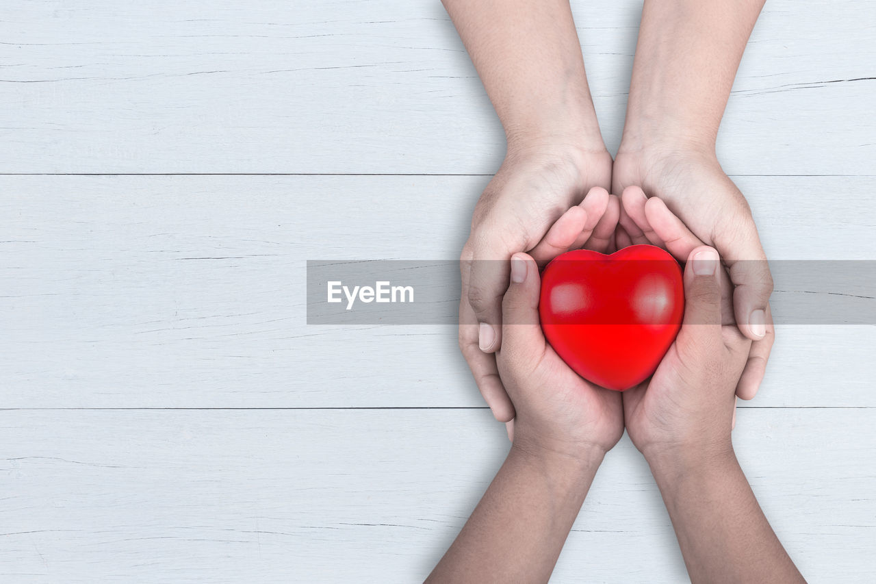 Directly above shot of people holding heart shape on table