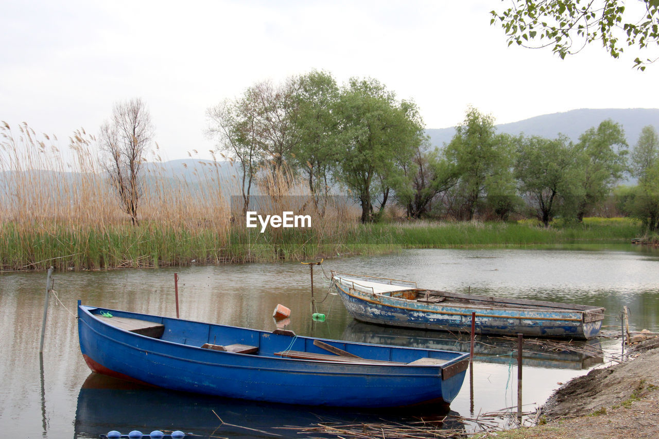 BOAT MOORED ON LAKE AGAINST SKY