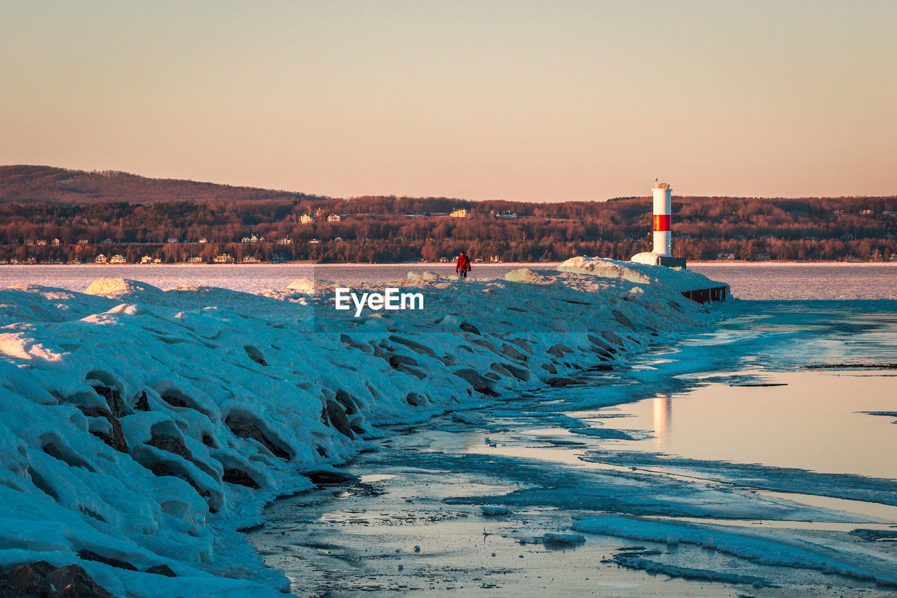 Tourist visiting a frozen lighthouse in petoskey michigan at sunset