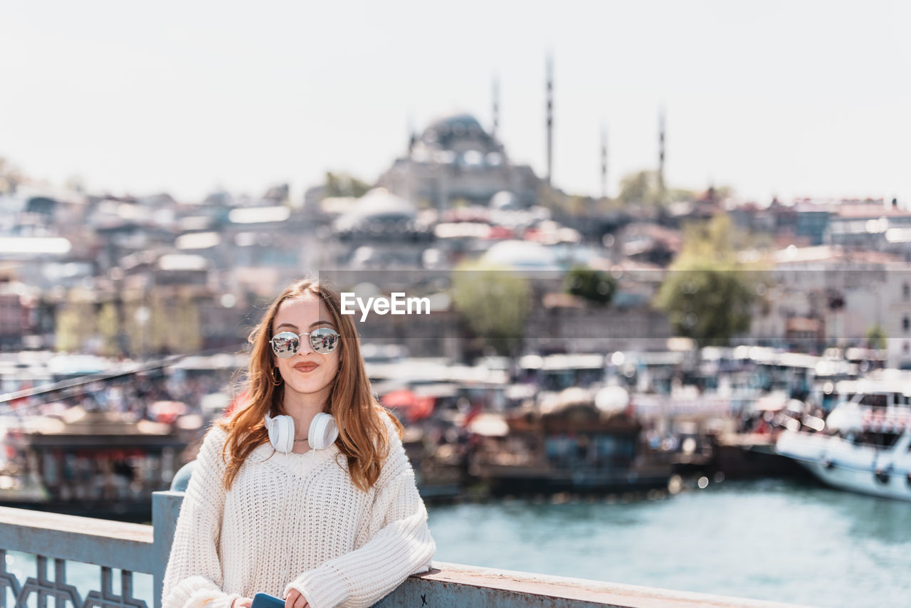 PORTRAIT OF BEAUTIFUL YOUNG WOMAN AGAINST BUILDINGS