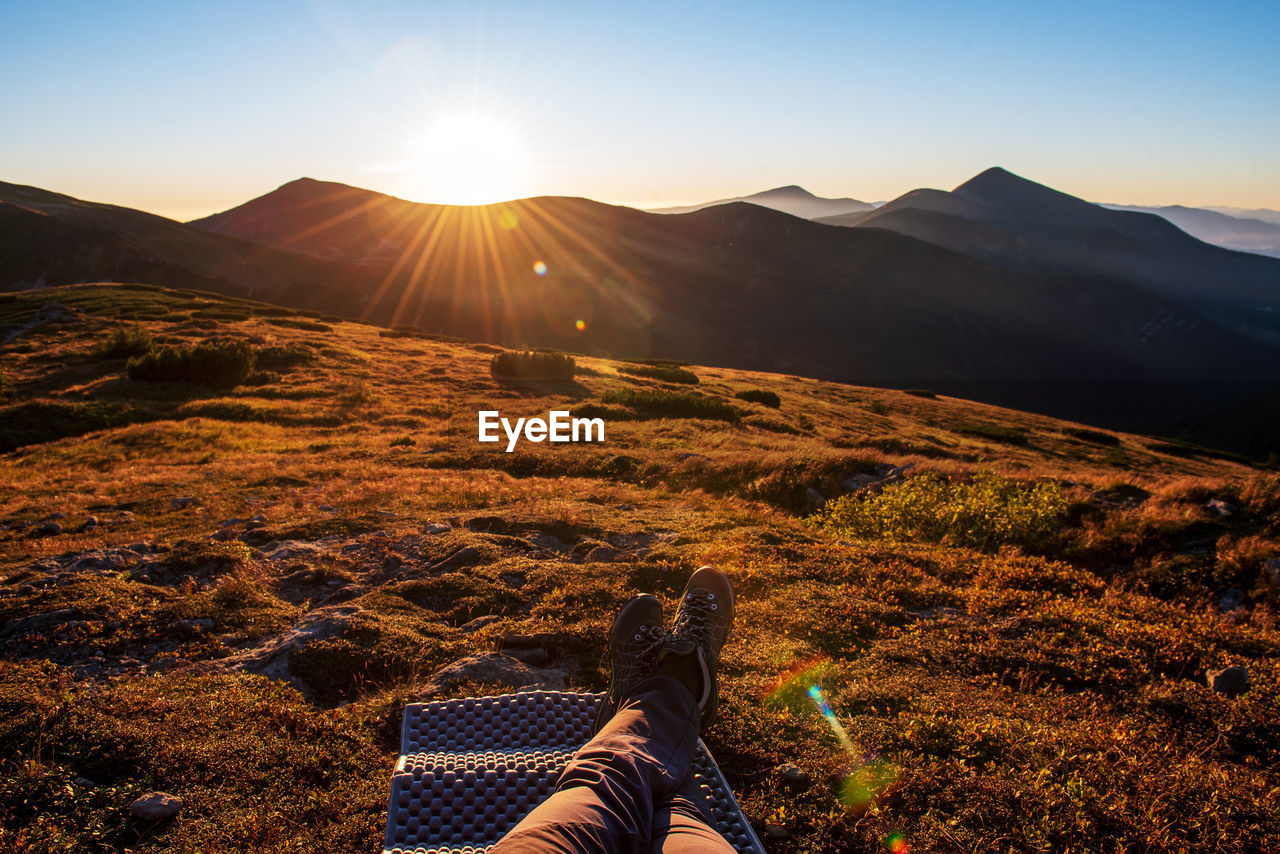 Low section of person on mountain against sky