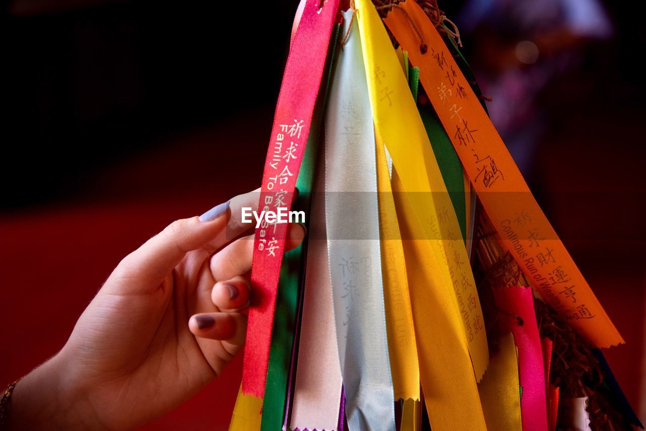 Cropped hand of woman touching multi colored ribbon for sale at market stall