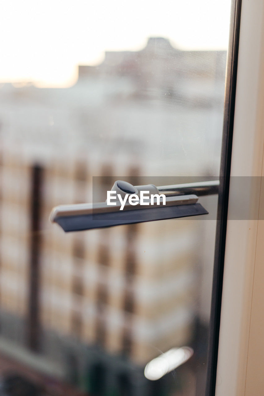 window, door handle, focus on foreground, glass, no people, day, iron, architecture, close-up, indoors, door, lighting, entrance, window covering, reflection